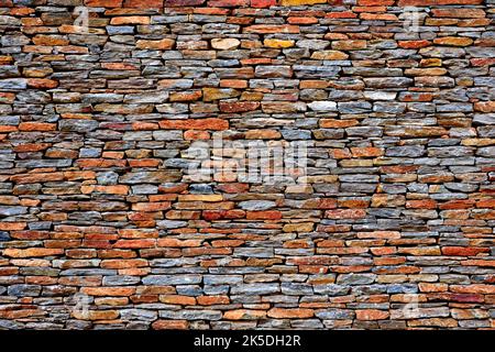 Layered stacked stone wall, different colors, odd sizes, earth tones Stock Photo