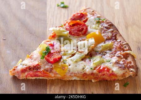 One slice of pizza  with salami, pepperoni peppers, tomatoes and onions -  close up view Stock Photo