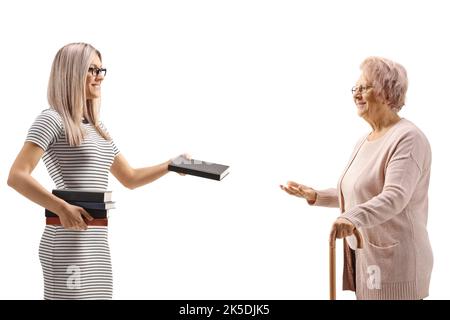 Profile shot of a young woman giving a book to an elderly woman isolated on white background Stock Photo