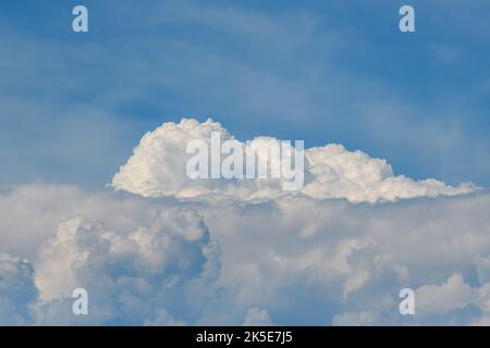 A large fluffy white cloud below a blue sky on a bright sunny day. Stock Photo