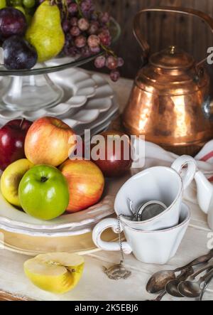 Autumn fruits, plates, cutlery and kitchen utencils on wooden table. Grapes, apples and pears on table. Stock Photo