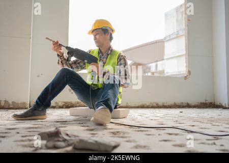 Construction worker Using an electric jackhammer to drill perforator equipment making holes before pouring the floor to be strong at construction site Stock Photo