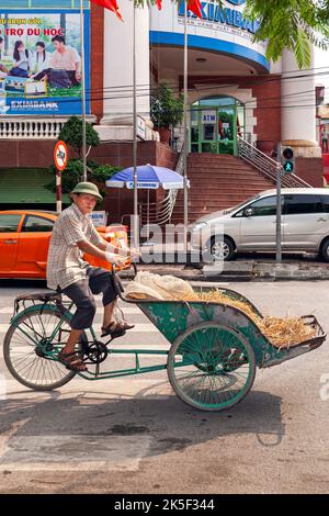 Vietnamese man using bicycle rickshaw to move construction material, Hai Phong, Vietnam Stock Photo