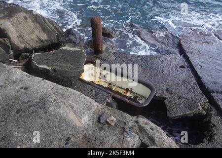 Rusty old Bathtub among Coastal Rocks Stock Photo