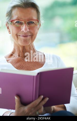 This is my favourite way to relax. Portrait of a smiling senior woman reading a good book at home. Stock Photo