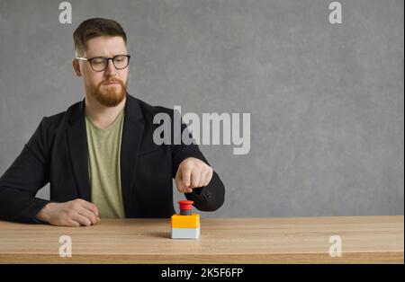 Young man pushes big red button to activate something or to get access to something Stock Photo