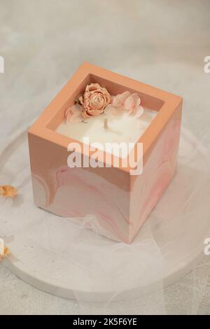 Soy candle in a concrete, plaster candlestick, decor interior. Home decoration with a burning scented candle. Gypsum, concrete products. Selective foc Stock Photo