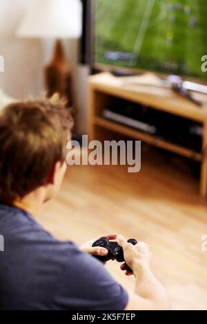Engrossed in the game. Handsome guy playing a video game using a controller. Stock Photo
