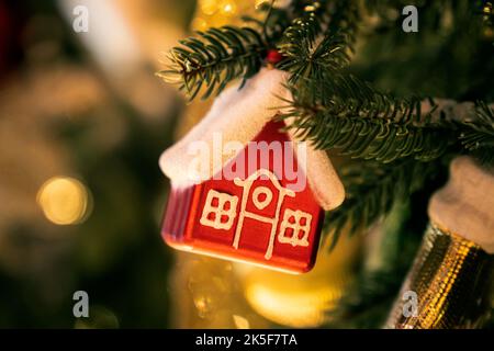 Christmas tree toy in form of a house on a branch. Christmas mood background. Vacation atmosphere. Chousing rental concept, realtor services, mortgage Stock Photo