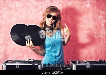 Hip and funky young dj. Playful portrait of a dj gesturing and holding two vinyl records. Stock Photo