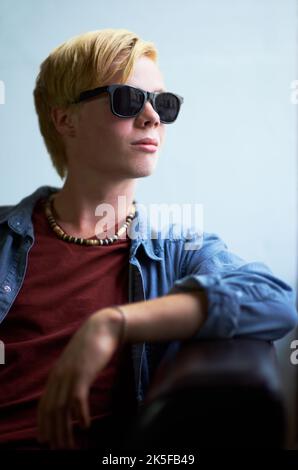 Thinking about his future. Attractive young guy wearing hipster shades and looking away. Stock Photo