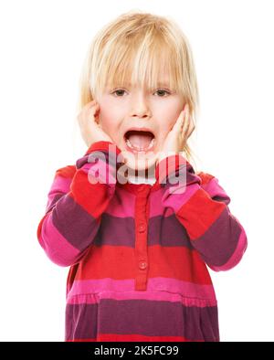 Thats scary. Studio shot of a little blonde girl standing with her head in her hands looking scared. Stock Photo