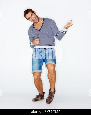 Rocking out. Handsome young guy playing air guitar while against a white background. Stock Photo