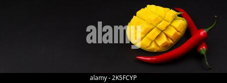 Diced mango and whole chili peppers on dark background. Ingredients for salsa. Banner. Stock Photo