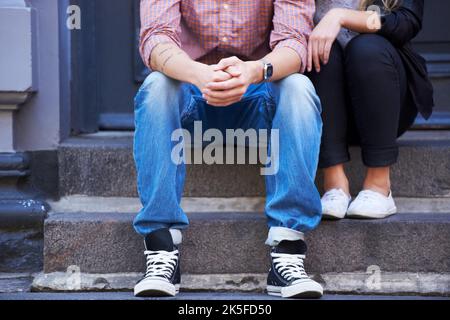 Taking in the neighborhoods atmosphere. Cropped image of a young couple sitting on their doorstep. Stock Photo