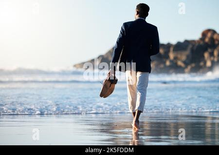 Business man relax at beach, walking on sand with shoes in hand and calm holiday at California sea. Sunset waves break on weekend, summer travel Stock Photo