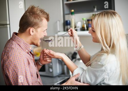 Tell me how it tastes. A young woman giving her boyfriend some food to taste. Stock Photo