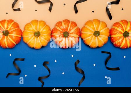 Halloween symbol concept, Scary smile pumpkins with dot are arranged on blue and cream background. Stock Photo