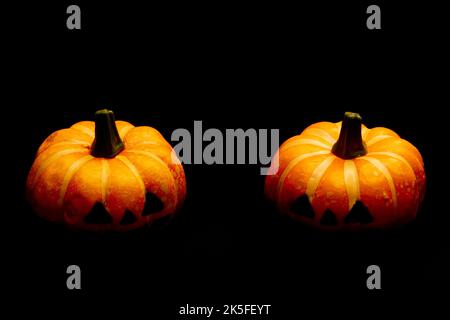 Halloween decorations concept, Two scary smiling pumpkins on black background. Stock Photo