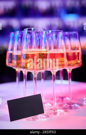 A blank black card with space for text against a Set of glasses with white wine in a nightclub Stock Photo