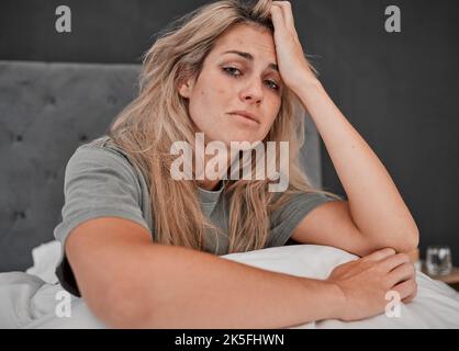 Depression, tired and portrait of a sick woman sitting on the bed in her bedroom at home. Anxiety, mental health problem and exhausted girl crying Stock Photo