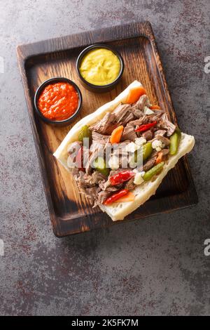 Italian beef sandwich originating in Chicago is composed of thin slices of seasoned roast beef, simmered and served au jus on a long French Roll close Stock Photo