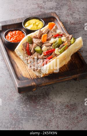 Italian beef sandwich originating in Chicago is composed of thin slices of seasoned roast beef, simmered and served au jus on a long French Roll close Stock Photo