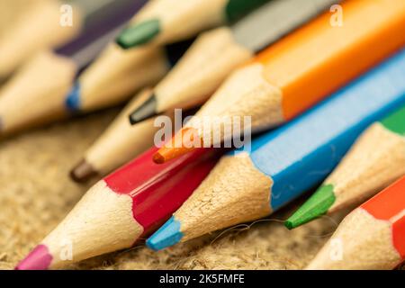 Several colored pencils of different colors on a background of coarse burlap. Close-up, selective focus Stock Photo