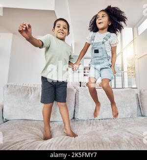 Children, brother and sister bonding and jumping on sofa in house, home or hotel living room in fun, play and energy game. Smile, happy or adhd kids Stock Photo