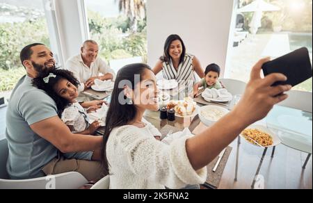 Big family, phone selfie and food in home, eating and spending time together on table. Generations, grandfather and parents with kids smiling sharing Stock Photo