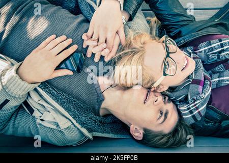 Couple at the beginning of a love story - Close up of happy hipster lovers - Youth concept  on a wood grey floor background - Retro clothes and sungla Stock Photo