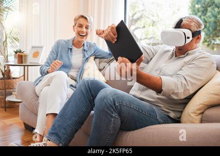 Virtual reality, 3d and digital gaming senior couple online in living room with futuristic metaverse technology. VR, esports and tech with a man gamer Stock Photo