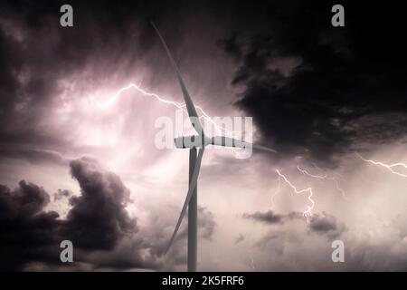 Wind electric turbine clean and green renewable energy generation with dramatic sky behind lightening electricity and thunder Stock Photo