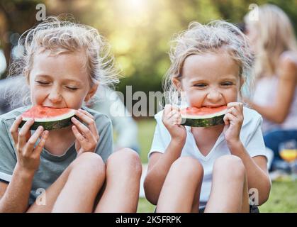 Happy, picnic and watermelon with children in park with family for summer, wellness and relax. Health, nature and spring with kids eating fruit in Stock Photo