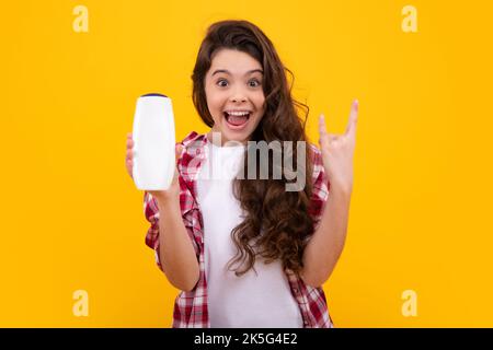 Amazed teenager. Teenage girl with shampoos conditioners or shower gel. Kids hair care cosmetic product, shampoo bottle. Excited teen girl. Stock Photo
