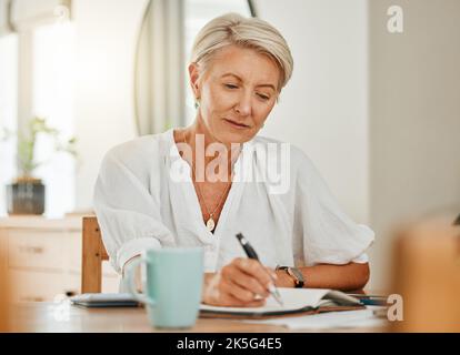 Writing, thinking and senior woman at a house making notes on notebook paper. Retirement of a serious person from Sweden think about schedule, day Stock Photo