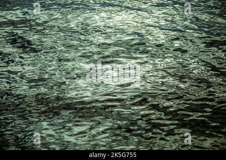 Texture formed by the rounded and curved waves of the water and the waves of the sea with gray and bluish tones and light reflections Stock Photo