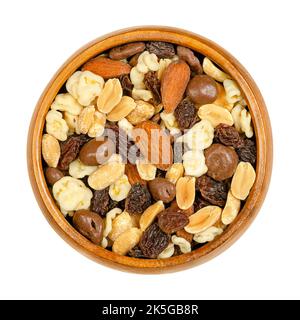 Nut chocolate mix, in wooden bowl. Sweet snack food and mixture of raisins, roasted peanuts and almonds, with milk and white chocolate. Stock Photo