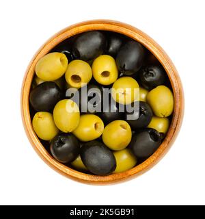 Pitted green and black olives, Hojiblanca, in a wooden bowl. European olives, Olea europaea. Popular table olives with a lower oil content. Stock Photo