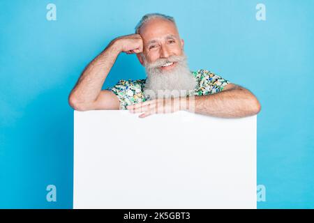Portrait of positive friendly granddad toothy smile behind empty space blank isolated on blue color background Stock Photo