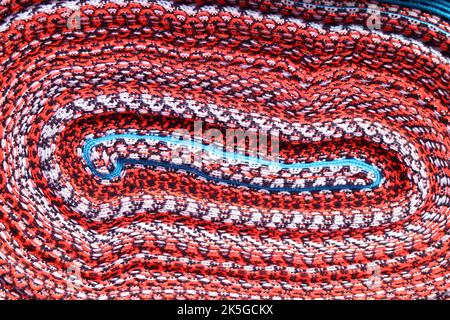 Vibrant colored curving lined of rolled up Peruvian fabric for sale in downtown Cuzco, Peru, South America Stock Photo