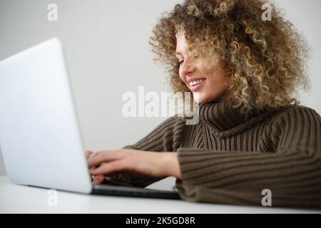Happy white woman typing text on laptop keyboard. Cheerful Ukrainian female person working on notebook computer Stock Photo