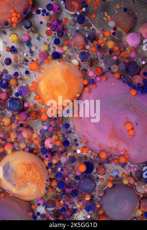 Acrylic paint balls abstract texture. Bright colors fluid, flowing wallpaper design. Purple, blue, pink and yellow liquids mix. Stock Photo