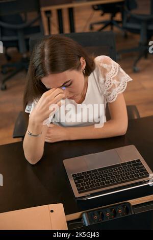 Tired female office worker suffering from headache at work Stock Photo