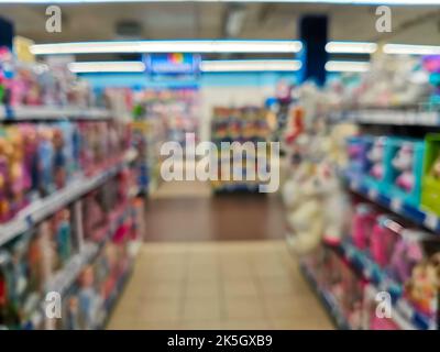 Abstract blur empty supermarket discount store aisle and product shelves interior defocused background. Rows of shelves with toys in a hypermall. Blur Stock Photo