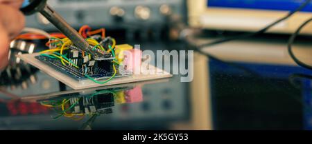 Manufacturing and setting up an electronic device in the laboratory. Soldering iron and electronic measuring instruments Stock Photo