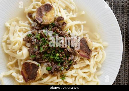 Lagman with Qazı is a traditional sausage food from horse meat, vegetables and pulled long noodles, include Bulgarian peppers, eggplants, radish, pota Stock Photo