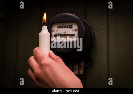 Checking old retro electric meter with candle light. Selective focus on fire. Stock Photo