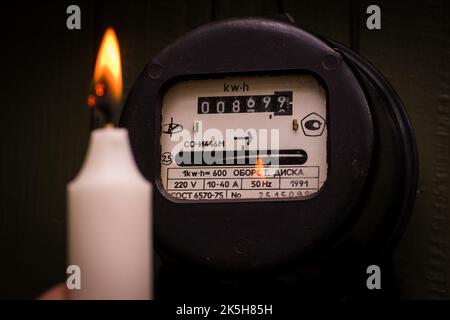 Checking old retro electric meter with candle light. Selective focus on fire. Stock Photo