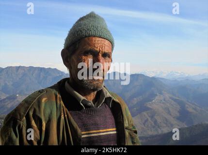 An old farmer looking at the camera with Indian Himalayans in the background Stock Photo